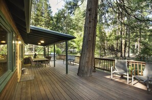 Ett trädäck med utemöbler, en pergola och utsikt över ett skogsområde.
