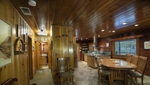A wooden interior with a dining area, kitchen, and a hallway leading to a bathroom.