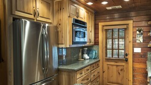 A kitchen with wooden cabinets, stainless steel appliances, granite countertops, and a wooden door with a window.