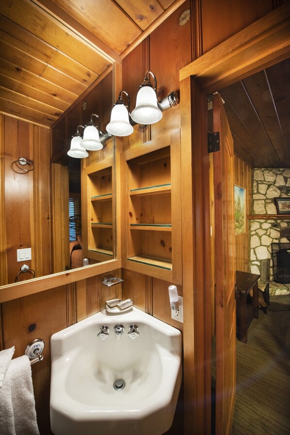 Un baño de madera con un espejo grande, un lavabo y repisas.