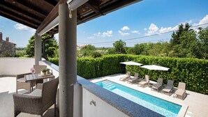 A rooftop pool area with lounge chairs and a table, surrounded by greenery and a clear sky. - Beautiful holiday home with heated swimming pool, summer kitchen, WiFi, grill (Vodnjan)