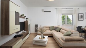 A modern living room with a sofa, TV, and a small table with a vase. - Beautiful holiday home with heated swimming pool, summer kitchen, WiFi, grill (Vodnjan)