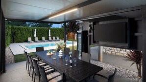 An outdoor patio with a pool, a dining table with chairs, and a flat-screen TV mounted on the wall. - Beautiful holiday home with heated swimming pool, summer kitchen, WiFi, grill (Vodnjan)
