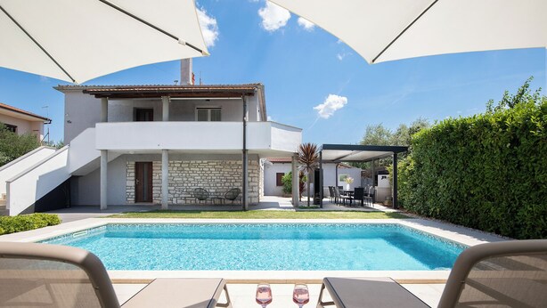 A modern villa with a swimming pool, outdoor seating, and a stone wall. - Beautiful holiday home with heated swimming pool, summer kitchen, WiFi, grill (Vodnjan)