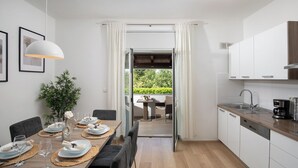 A modern kitchen with white cabinets, a wooden countertop, and a dining area with a table set for four. - Beautiful holiday home with heated swimming pool, summer kitchen, WiFi, grill (Vodnjan)