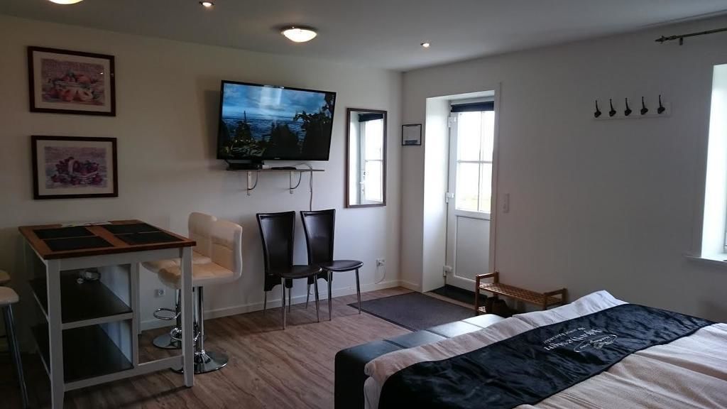 Une chambre d’hôtel avec un lit, un bureau avec des chaises, un téléviseur fixé au mur et une fenêtre.