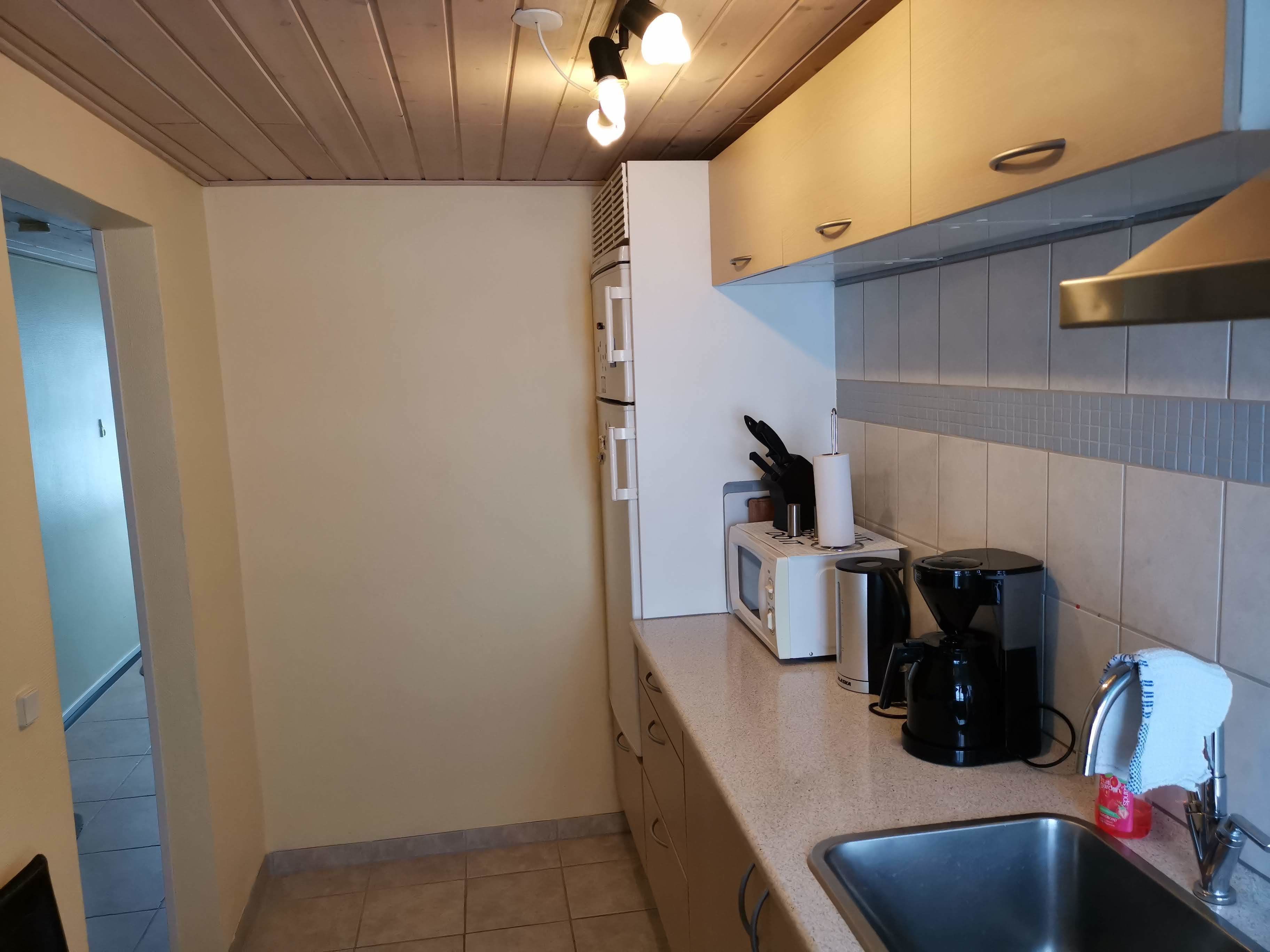 Een kleine keuken met een magnetron, koffiezetapparaat en spoelbak.