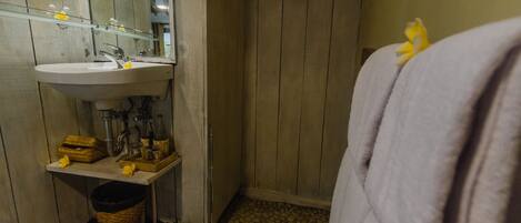 A bathroom with a wooden floor, a sink, a mirror, and a towel rack.