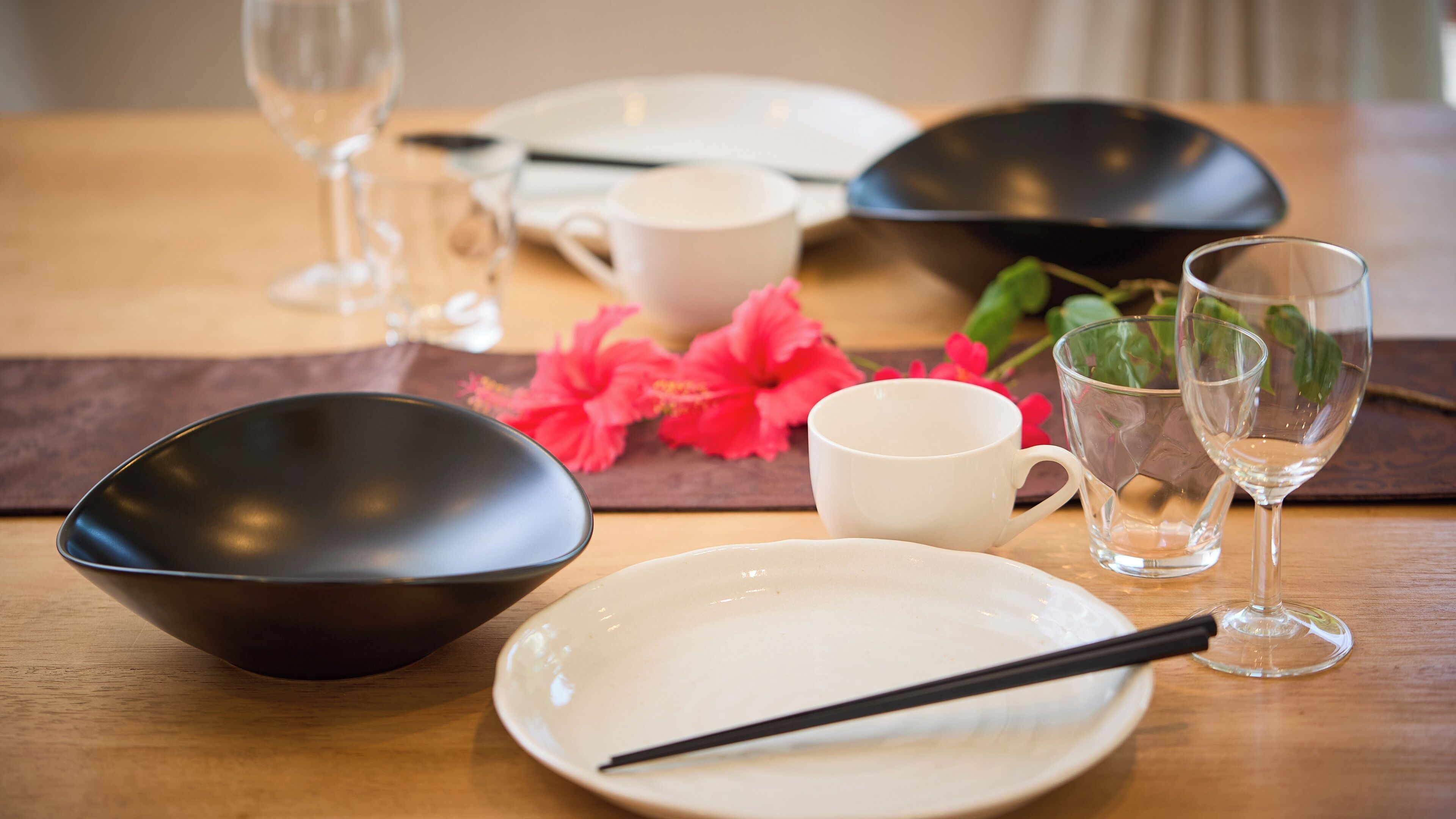 A dining table with various dishes, including a black bowl, a white plate, and a white cup.