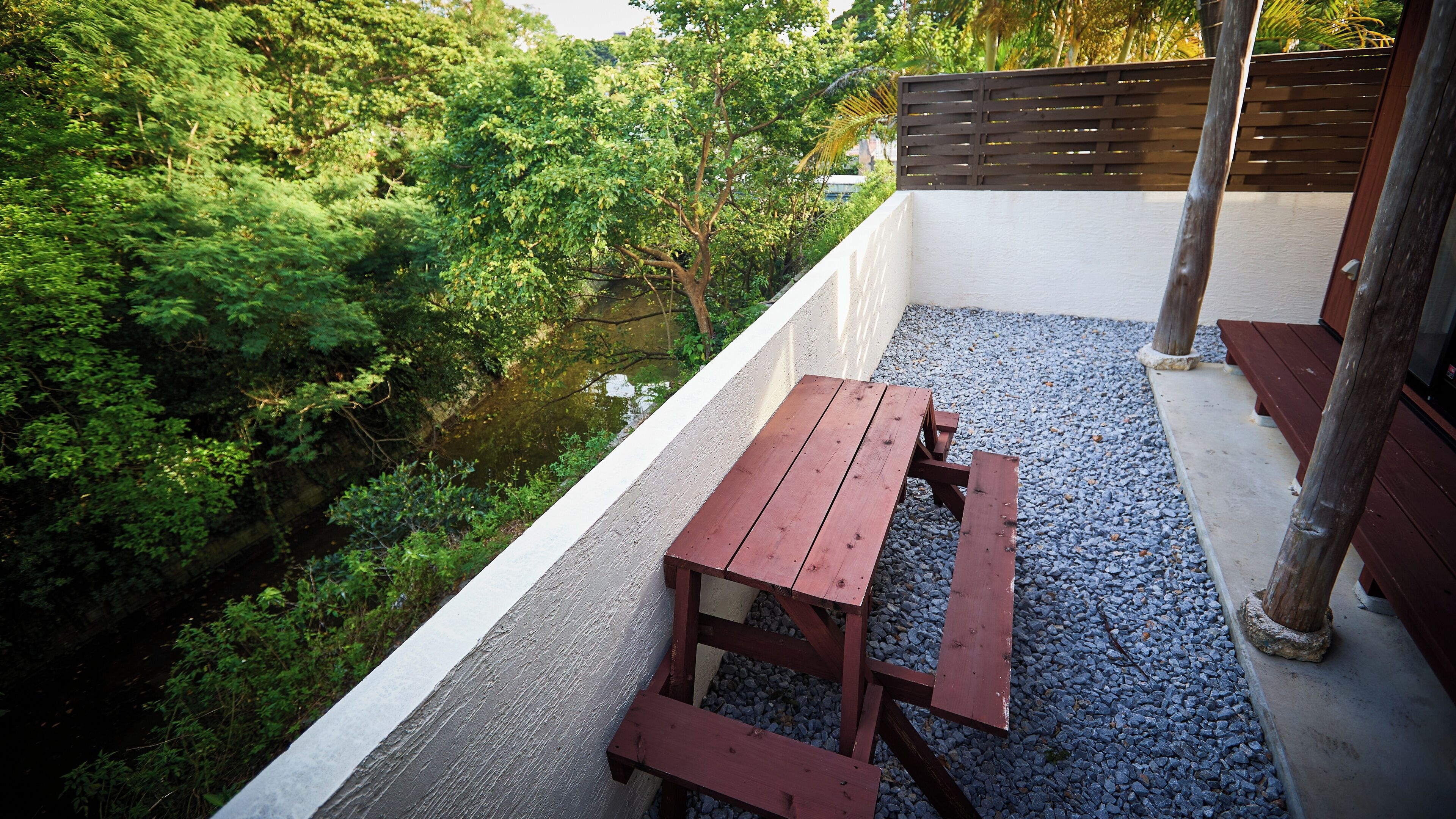 A wooden picnic table on a balcony with a view of a river and greenery.