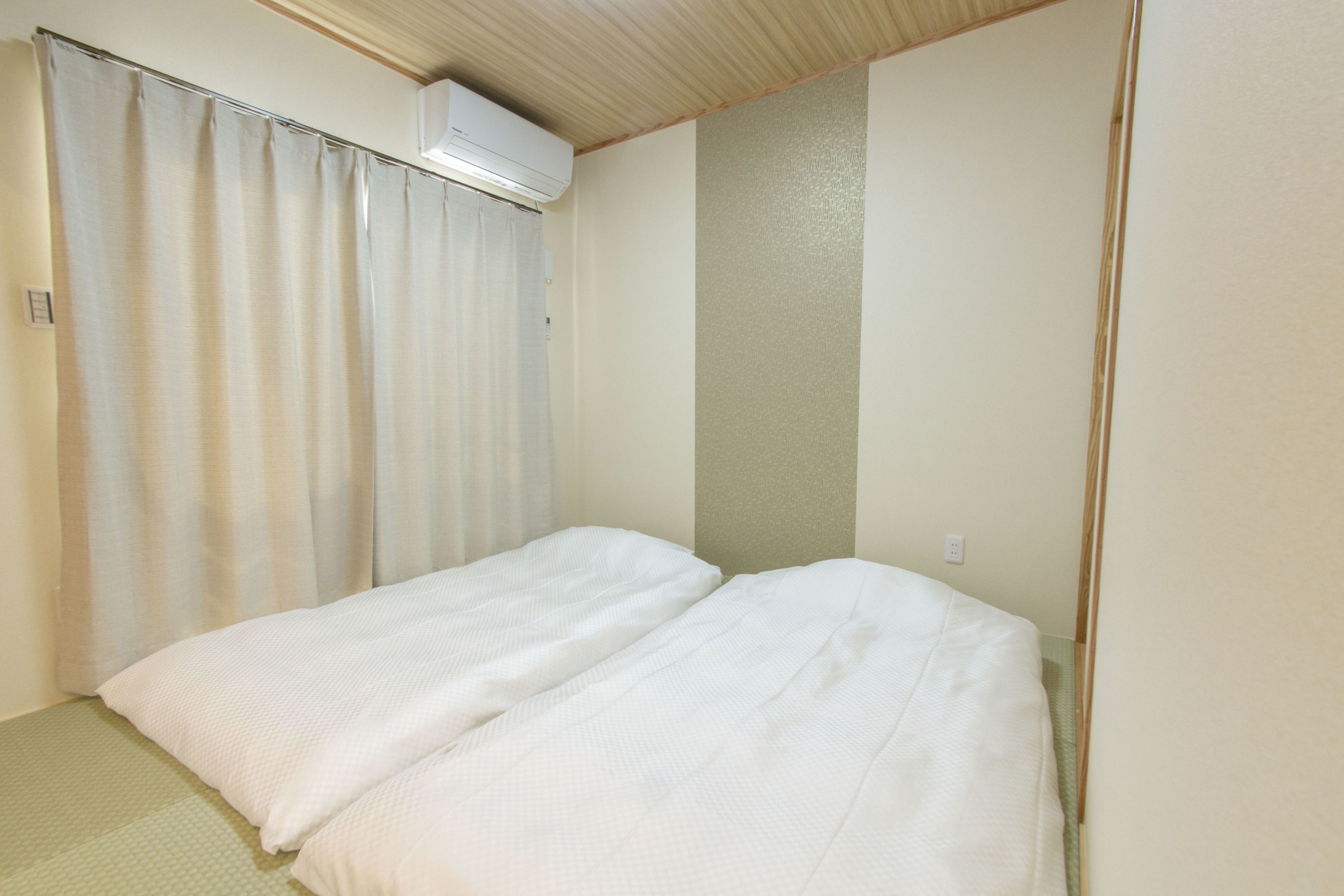 Une pièce avec un lit, un rideau et un appareil de climatisation fixé au mur.