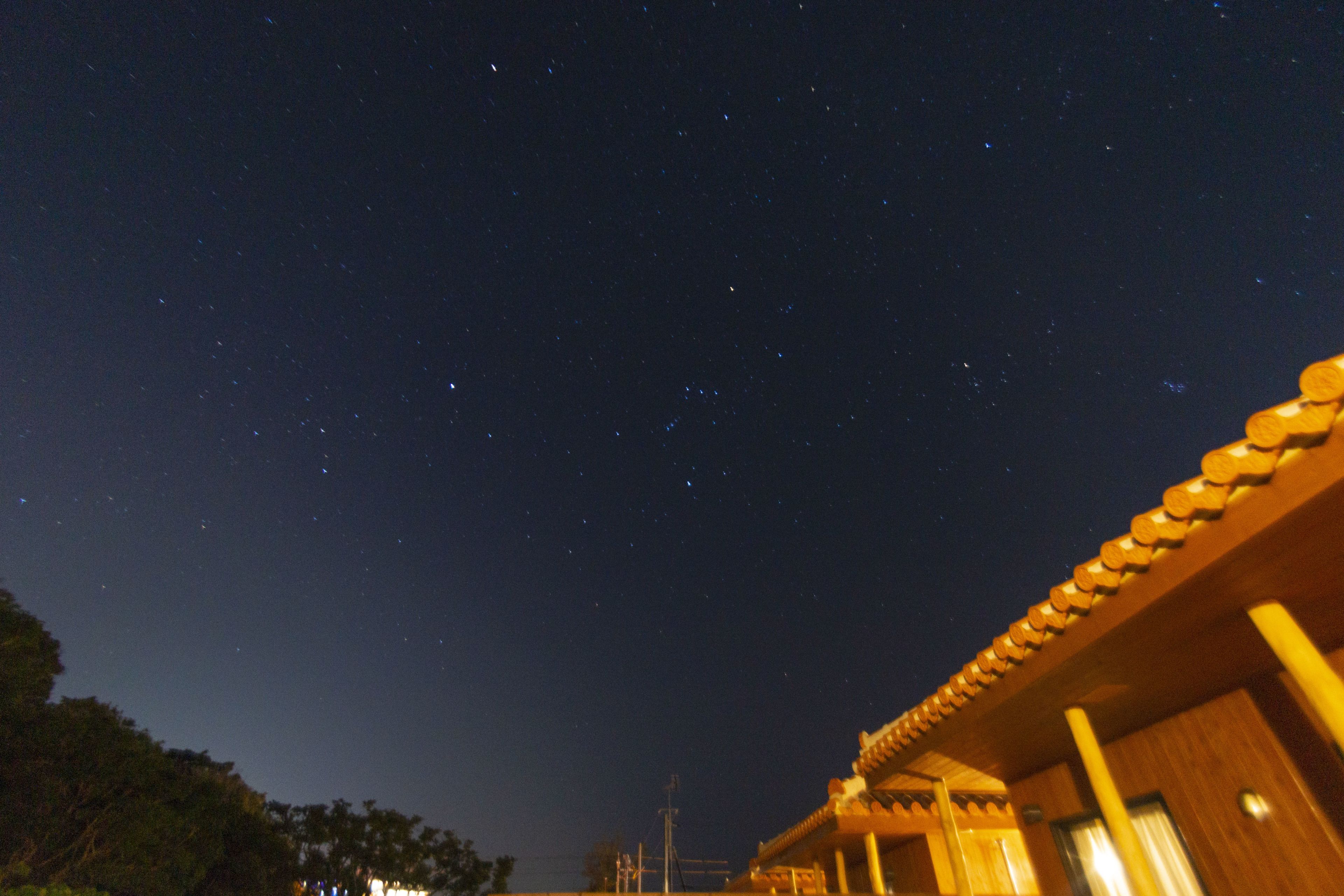 A traditional building with a tiled roof and wooden walls, under a starry night sky.