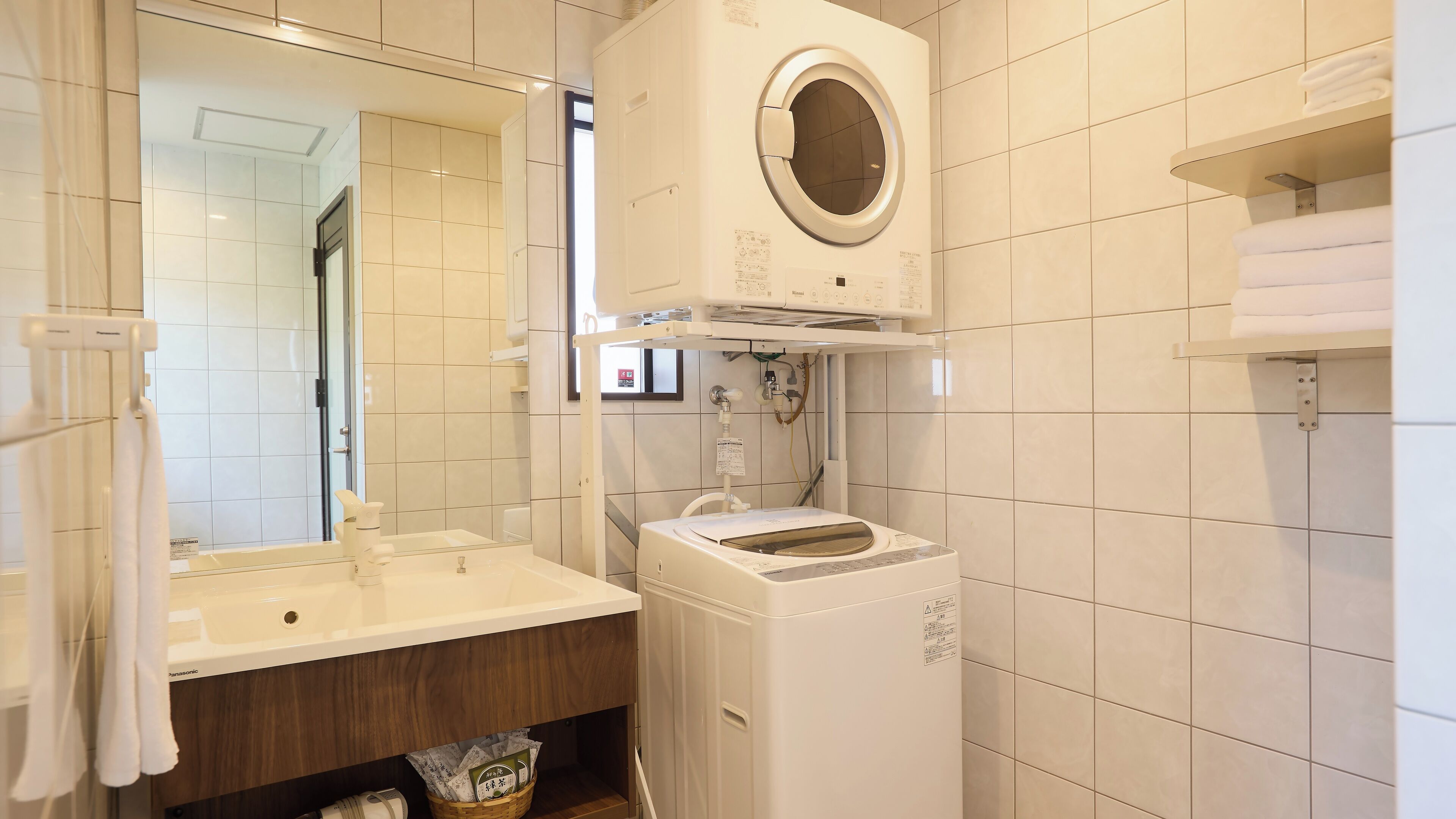 Moderni kylpyhuone, jossa on sisäänrakennettu pesukone, pesuallas ja peili.