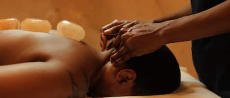 A massage therapy session with a person lying face down on a massage table, receiving a head massage.