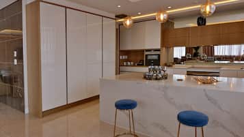A modern kitchen with a marble island, two bar stools, and pendant lighting.