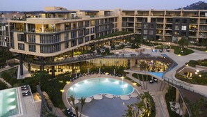 A multi-story hotel with a central courtyard pool, outdoor seating areas, and a landscaped garden. - The Houghton Hotel, Spa, Wellness & Golf (Johannesburg)
