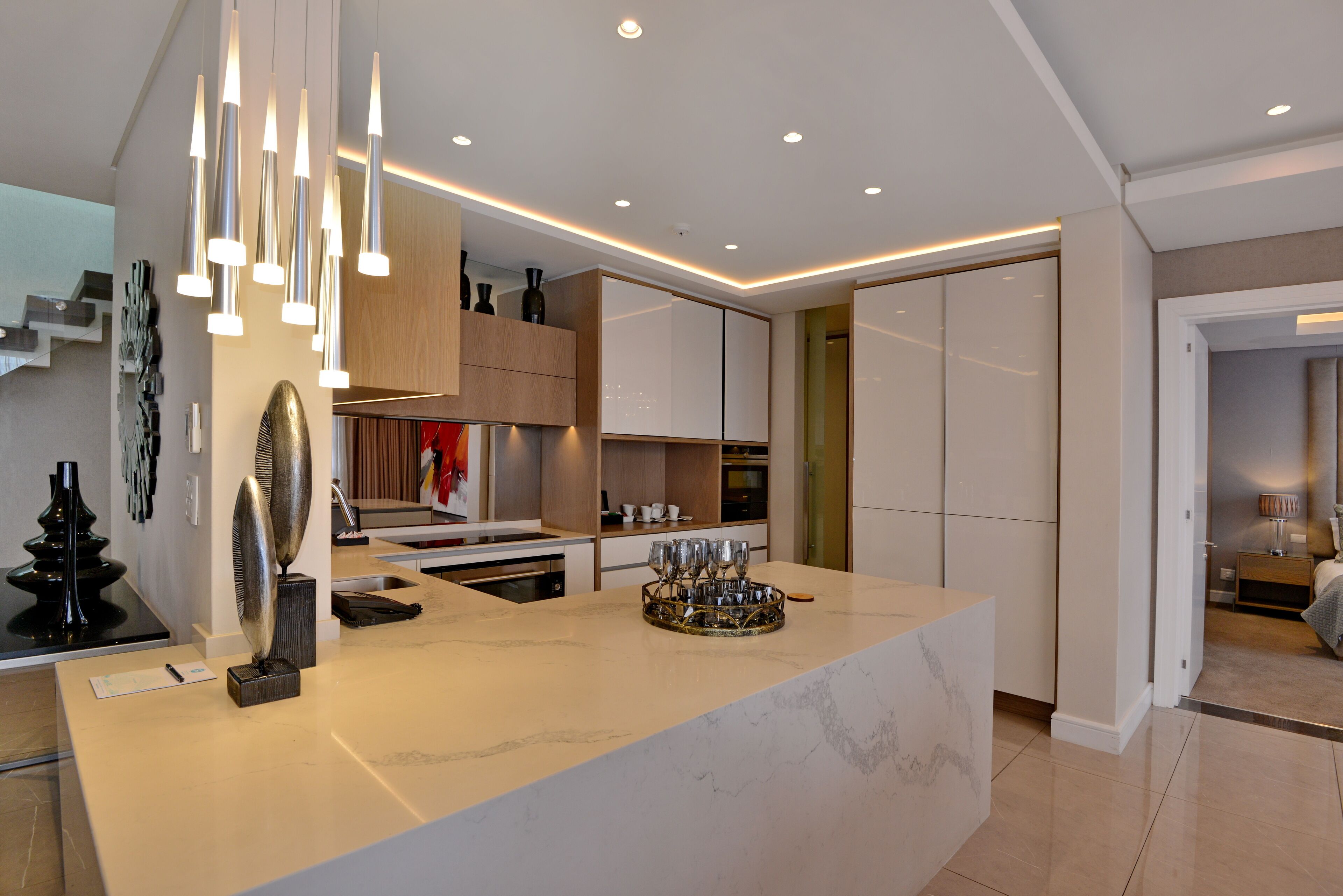 Una cocina moderna con encimera de mármol, luces colgantes y armarios empotrados.