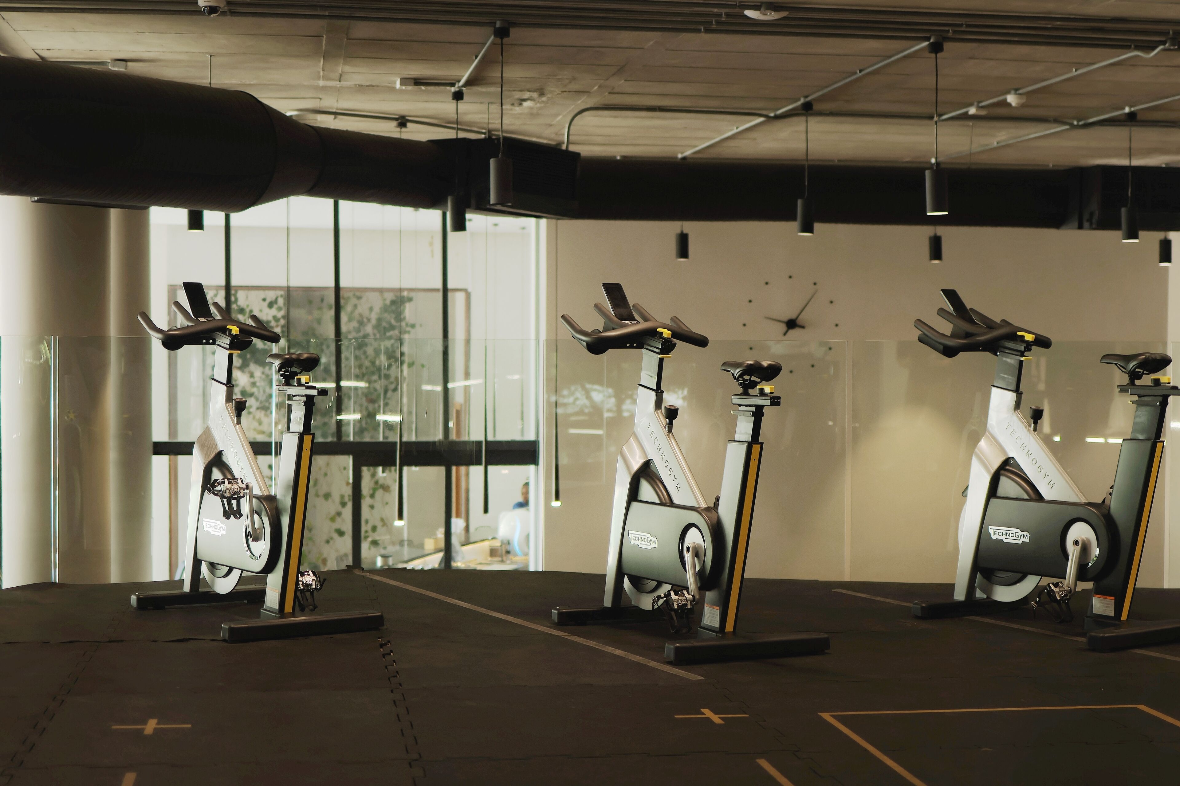 Un gimnasio con bicicletas estáticas y un amplio ventanal.