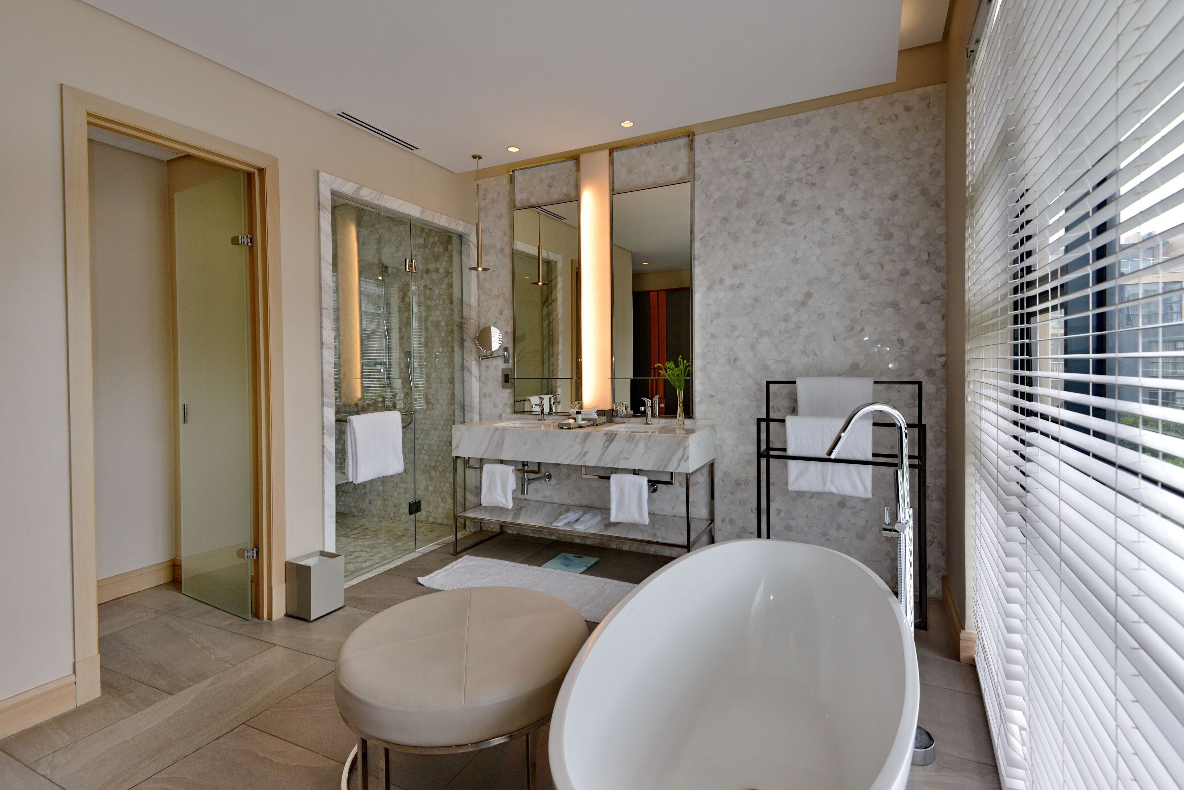 Ein modernes Badezimmer mit freistehender Badewanne, einer begehbaren Glasdusche und einem Waschtisch mit großem Spiegel.