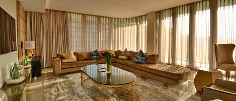 A spacious living room with a large sectional sofa, a glass coffee table, and a modern chandelier.