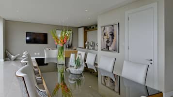 A modern dining area with a glass table, white chairs, and a vase with flowers.