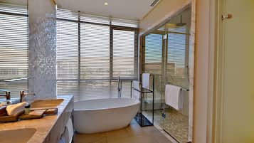 Un baño moderno con una bañera independiente, lavamanos dobles y una ducha con mampara de vidrio.
