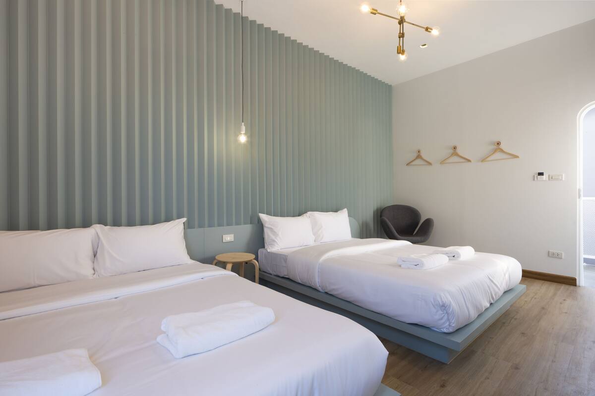 A hotel room with two beds, a small round table, and a chair.