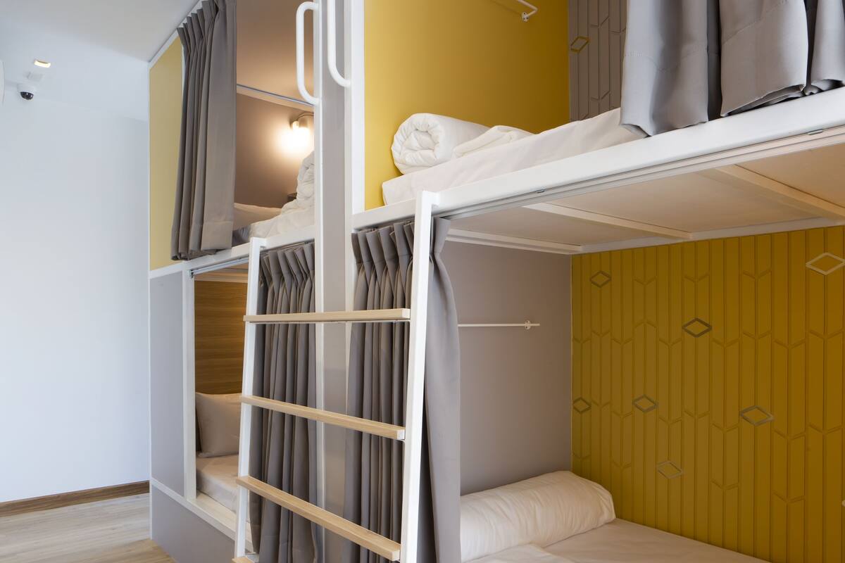 A bunk bed room with a ladder, a small shelf, and a wardrobe.