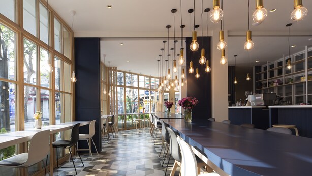A modern restaurant with a long counter, multiple seating areas, and hanging pendant lights. - Boxpackers Hostel Phranakorn (Bangkok)