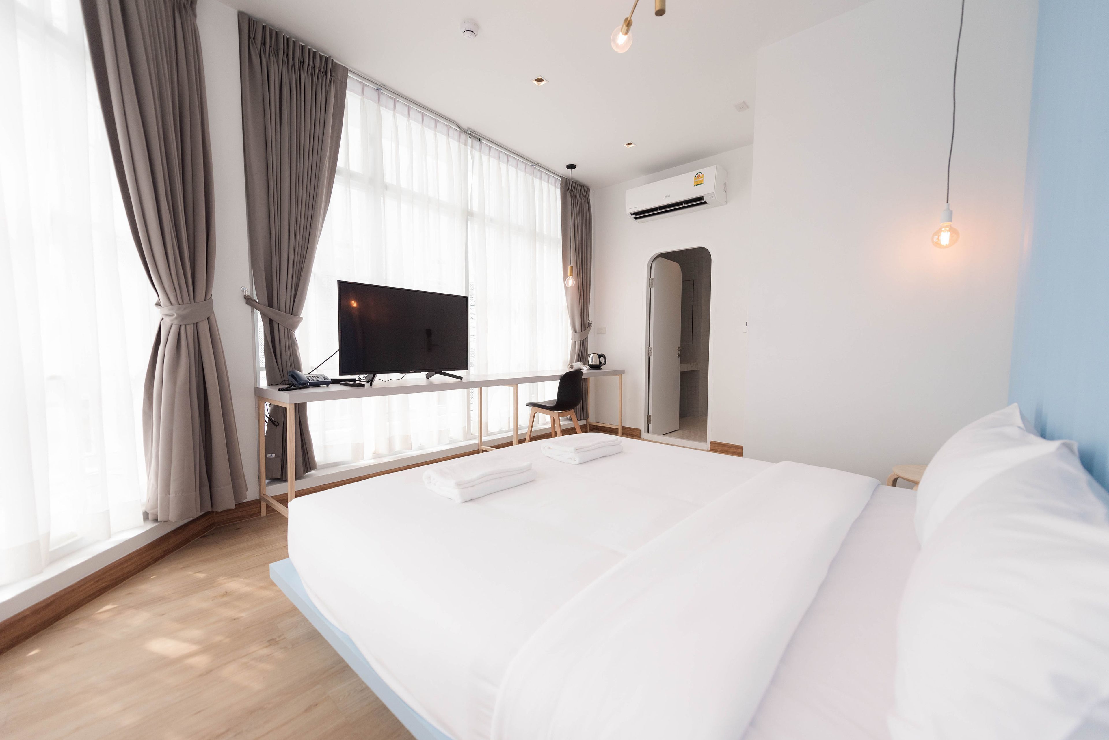 Een moderne hotelkamer met een groot bed, een bureau met flatscreen televisie, een stoel en een kledingkast.
