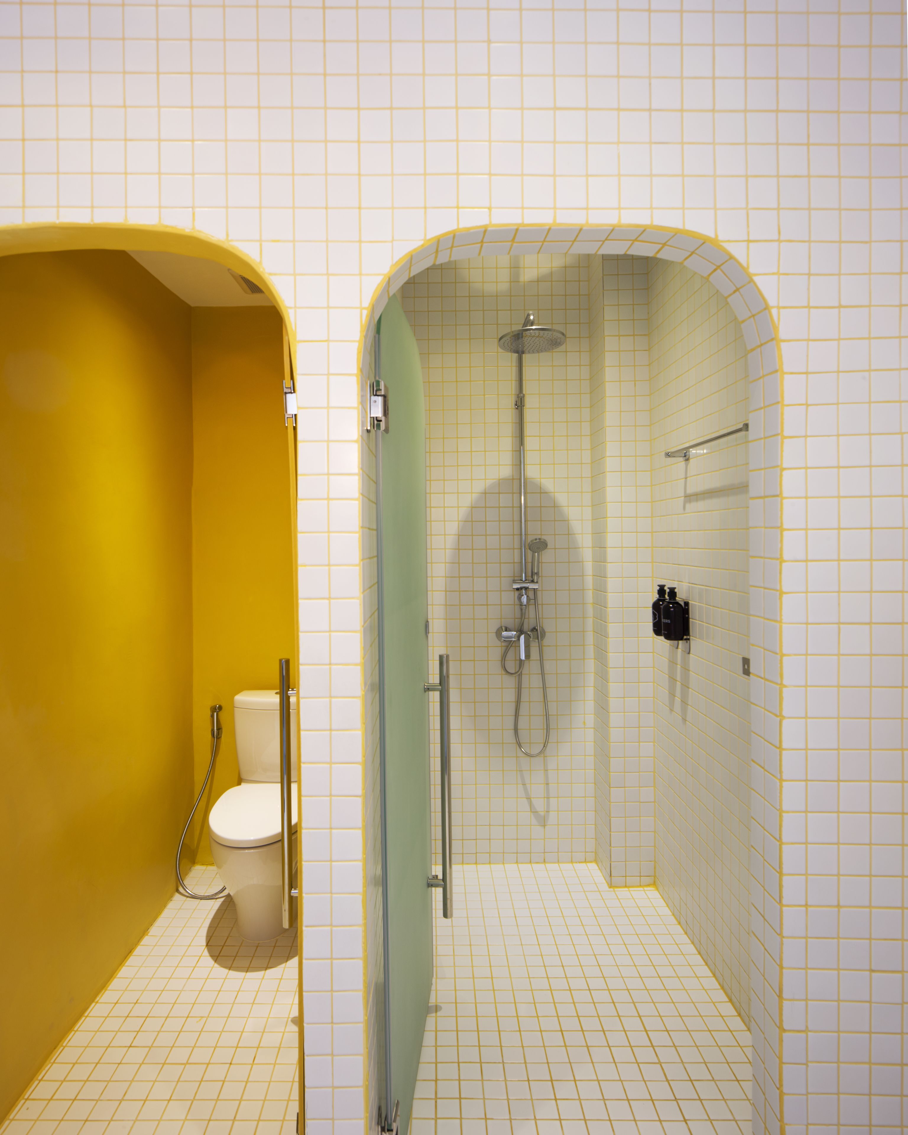 A bathroom with a yellow wall, a white toilet, and a shower area with a glass door.