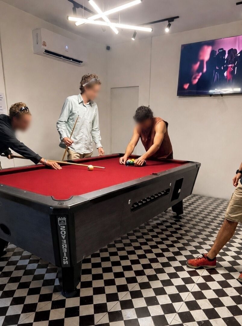 A pool table in a room with a checkered floor, a television mounted on the wall, and an air conditioning unit.