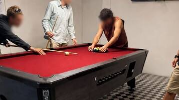 A pool table in a room with a checkered floor, a television mounted on the wall, and an air conditioning unit.