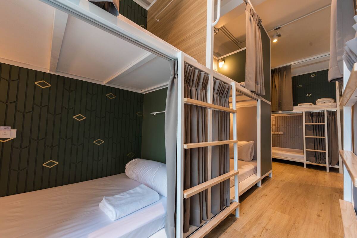 A modern hotel room with bunk beds, a wooden floor, and a geometric-patterned wall.