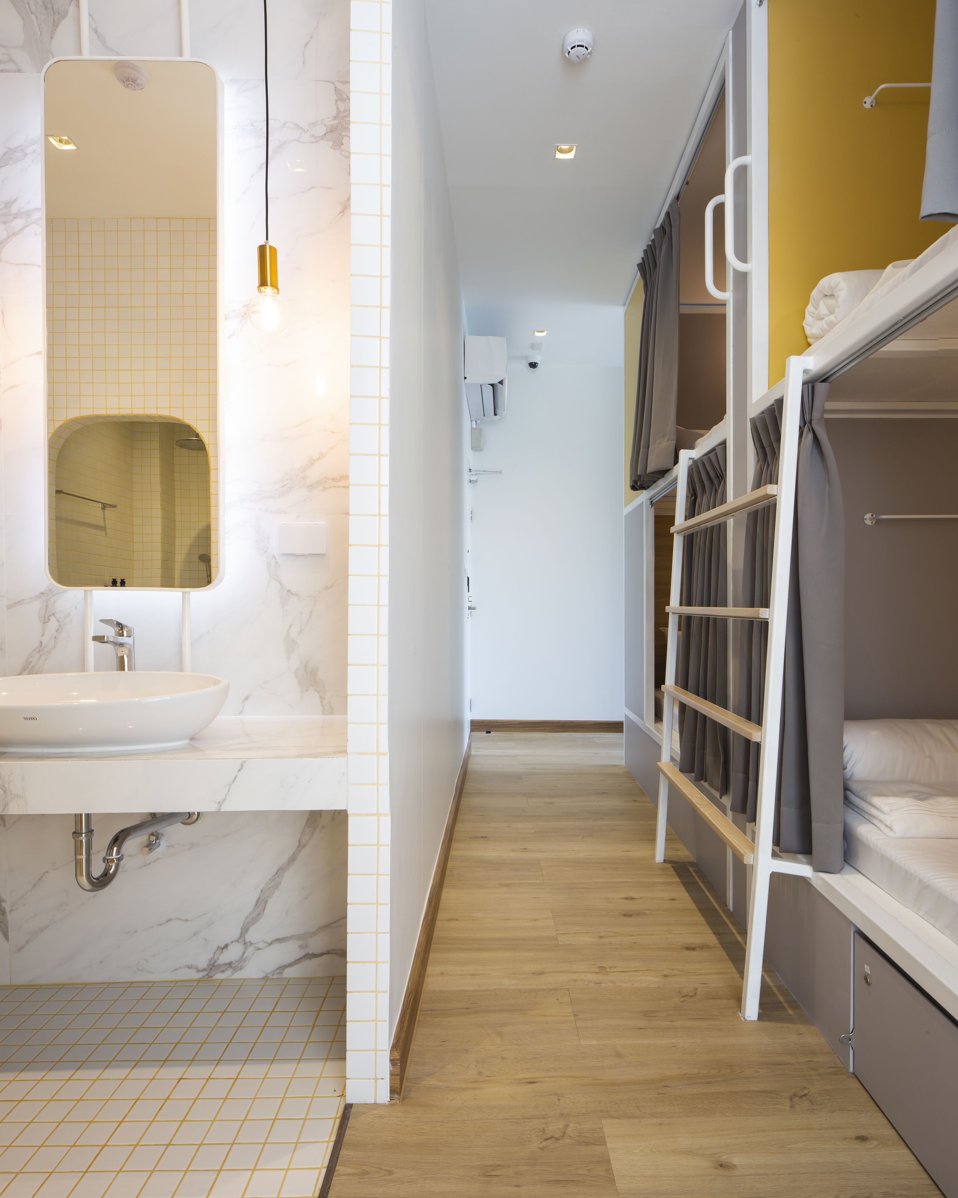 A modern bathroom with a marble sink, a mirror, and a wooden floor.