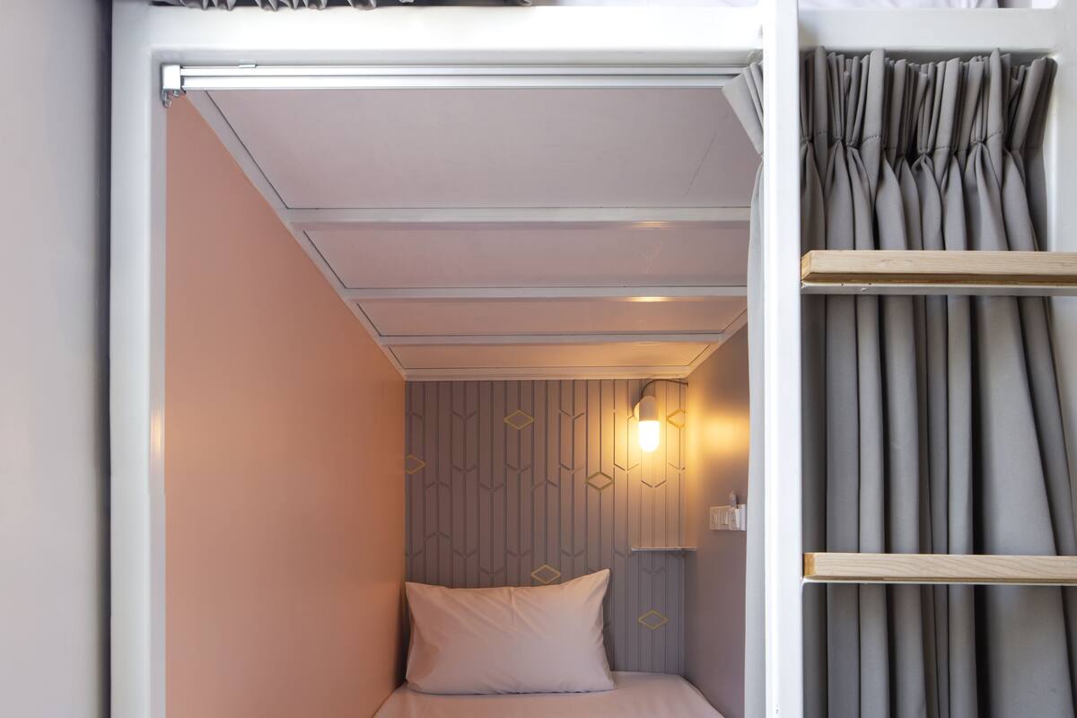 A bunk bed with a headboard, a bedside table, and a wall-mounted light fixture.