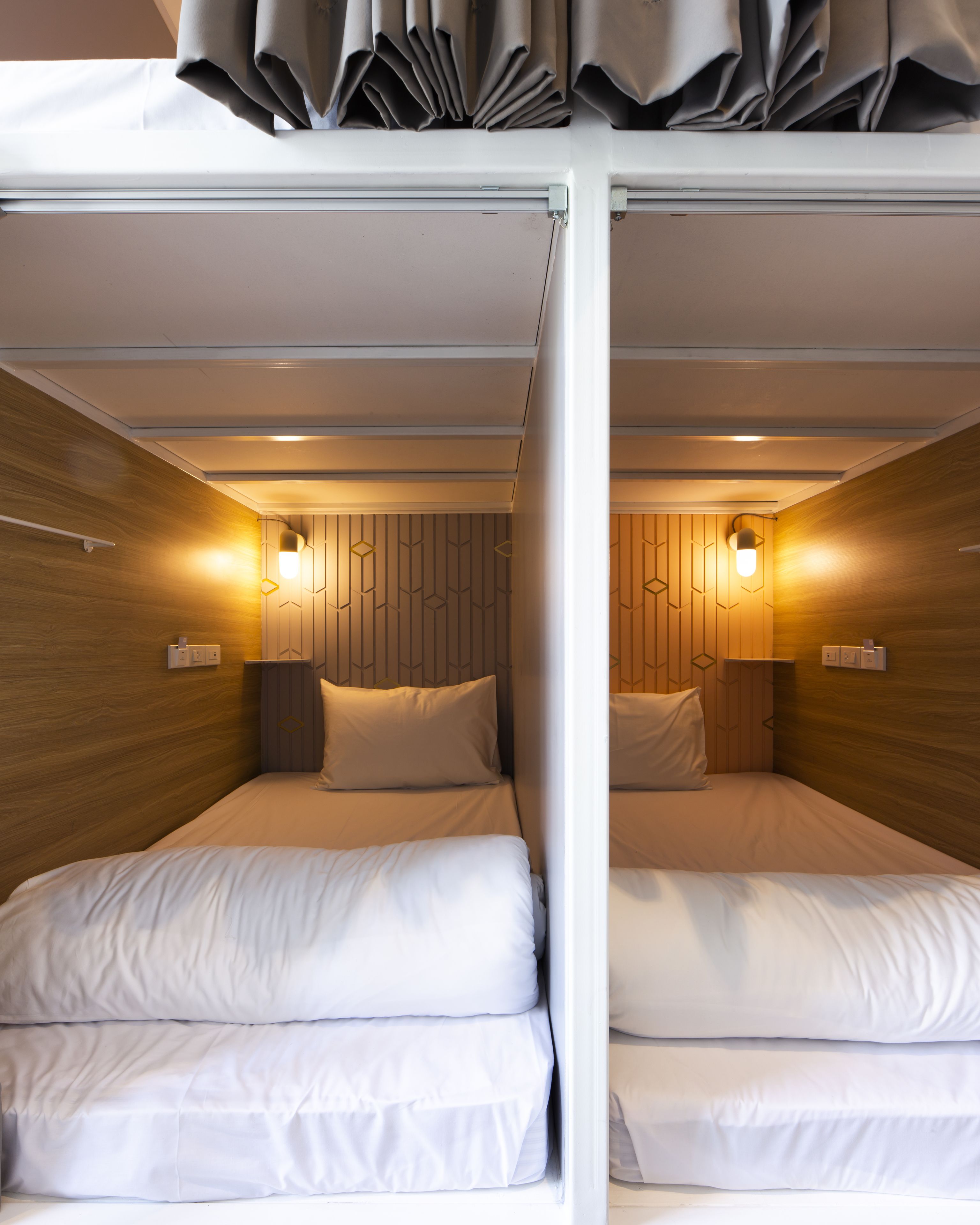 Een moderne, compacte kamer met twee bedden, houten lambrisering en wandlampen.