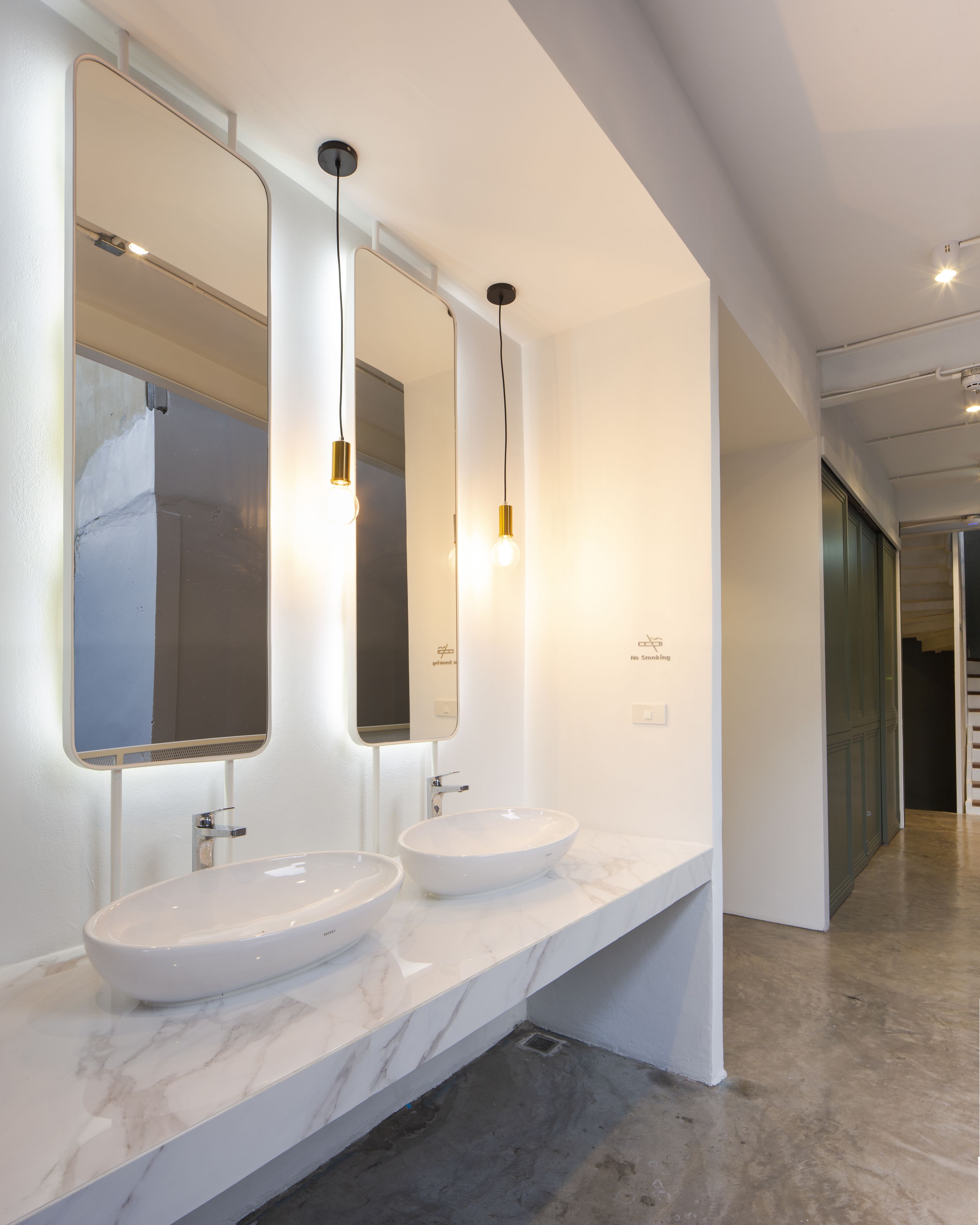 Un baño moderno con dos lavamanos, espejos grandes e iluminación colgante.
