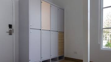 Una stanza con un ampio armadio bianco, pavimento in legno e una finestra vista alberi.