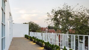 A rooftop terrace with a wooden deck, potted plants, and a white fence. - Boxpackers Hostel Phranakorn (Bangkok)