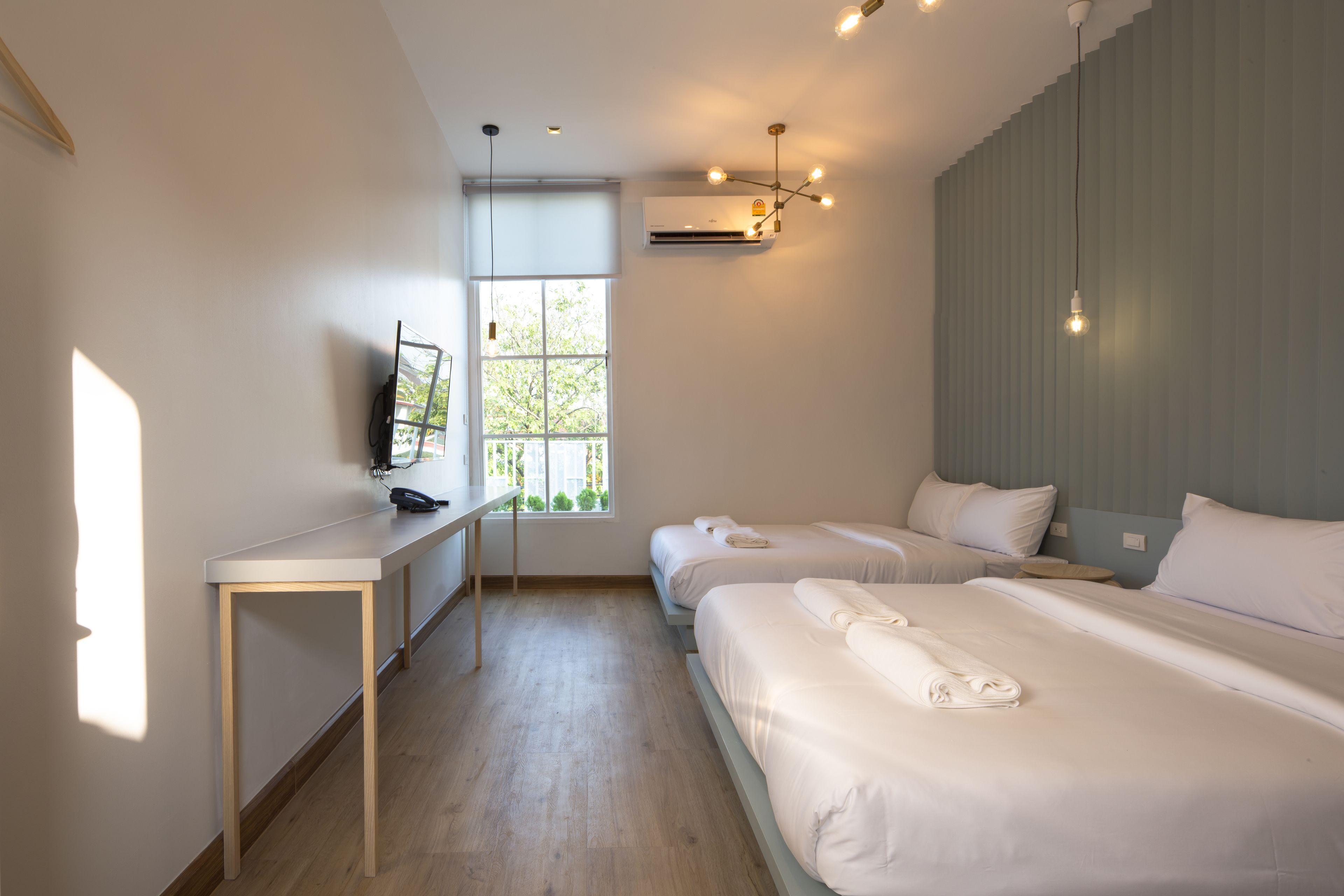 Moderni hotellihuone, jossa on kaksi sänkyä, työpöytä ja suuri ikkuna.