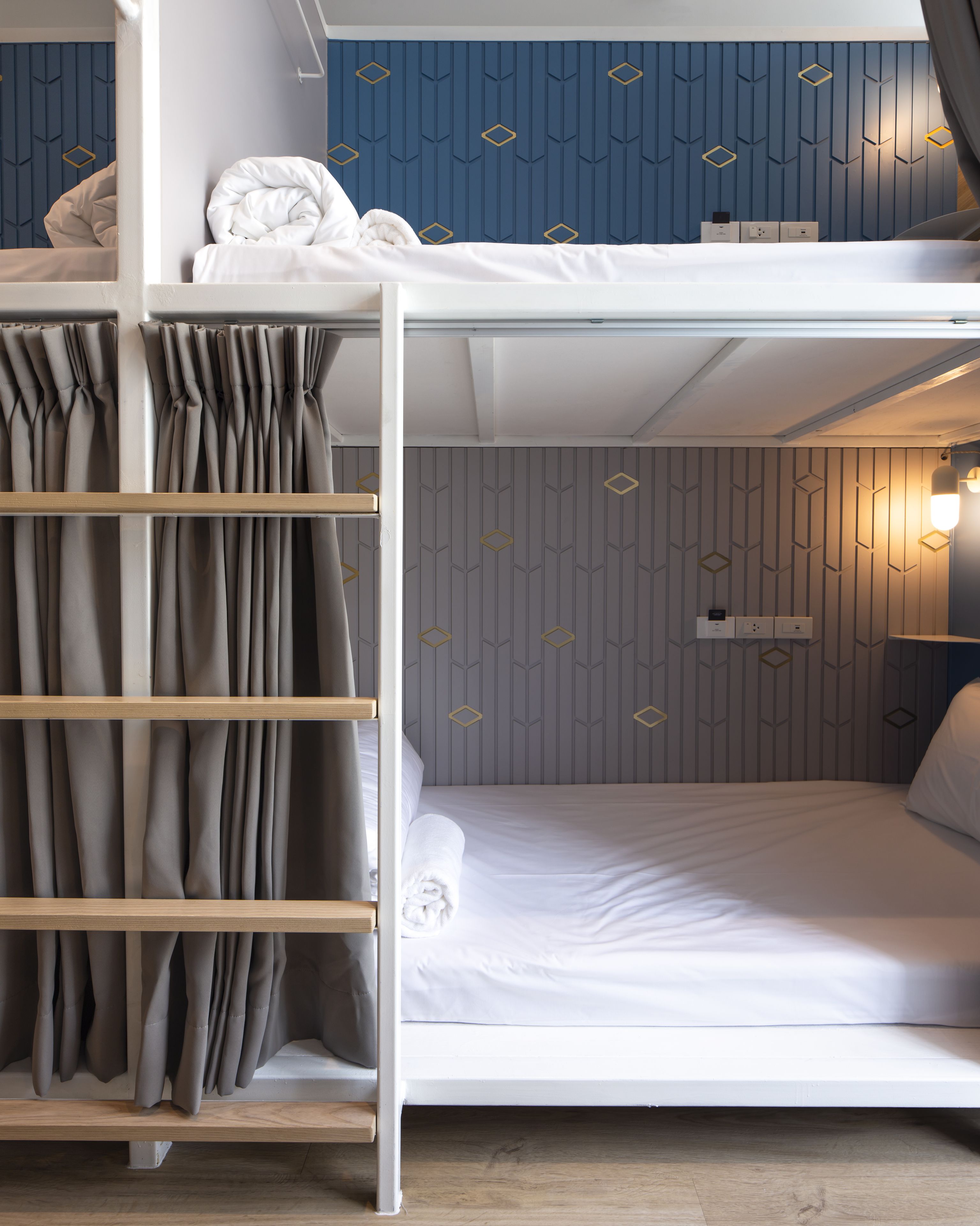 A bunk bed with a lower bunk, a bedside table with a lamp, and a curtain rail with curtains.