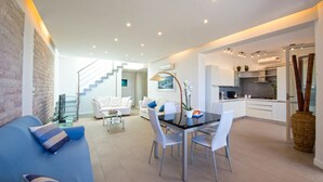 A modern living room with a glass dining table, white sofas, and a staircase leading to an upper level. - Villa Mondello Addaura Sea View (Palermo)