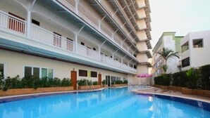 Een hotel met een zwembad, meerdere balkons en een modern architectonisch ontwerp.