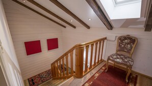 Eine Treppe mit Holzgeländern, einem roten Teppich und einem gemusterten Läufer.