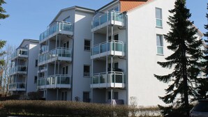A multi-story residential building with balconies, a flat roof, and a clear sky.