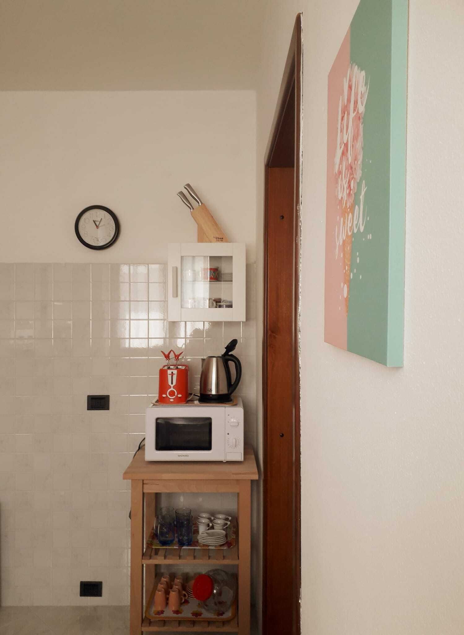 Eine Küche mit Mikrowelle, einer Uhr und einem Schrank mit Glastüren.