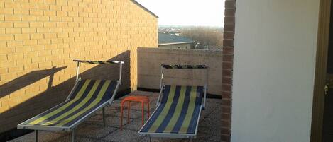 Terraza en la azotea con dos sillones de lounge y un taburete naranja.