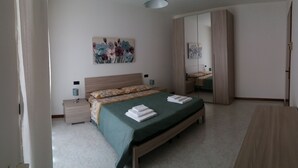 A bedroom with a bed, bedside tables, a nightstand, a mirror, and a wardrobe.