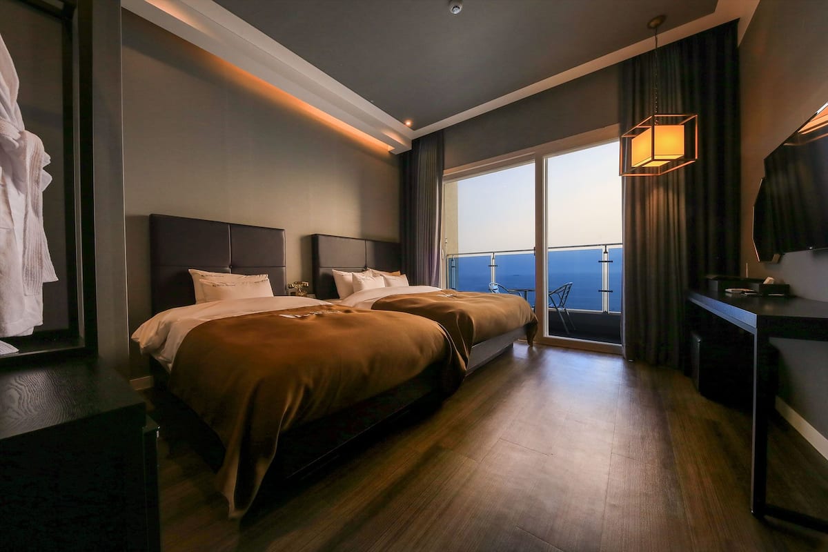 A hotel room with a large bed, a desk, and a view of the ocean.
